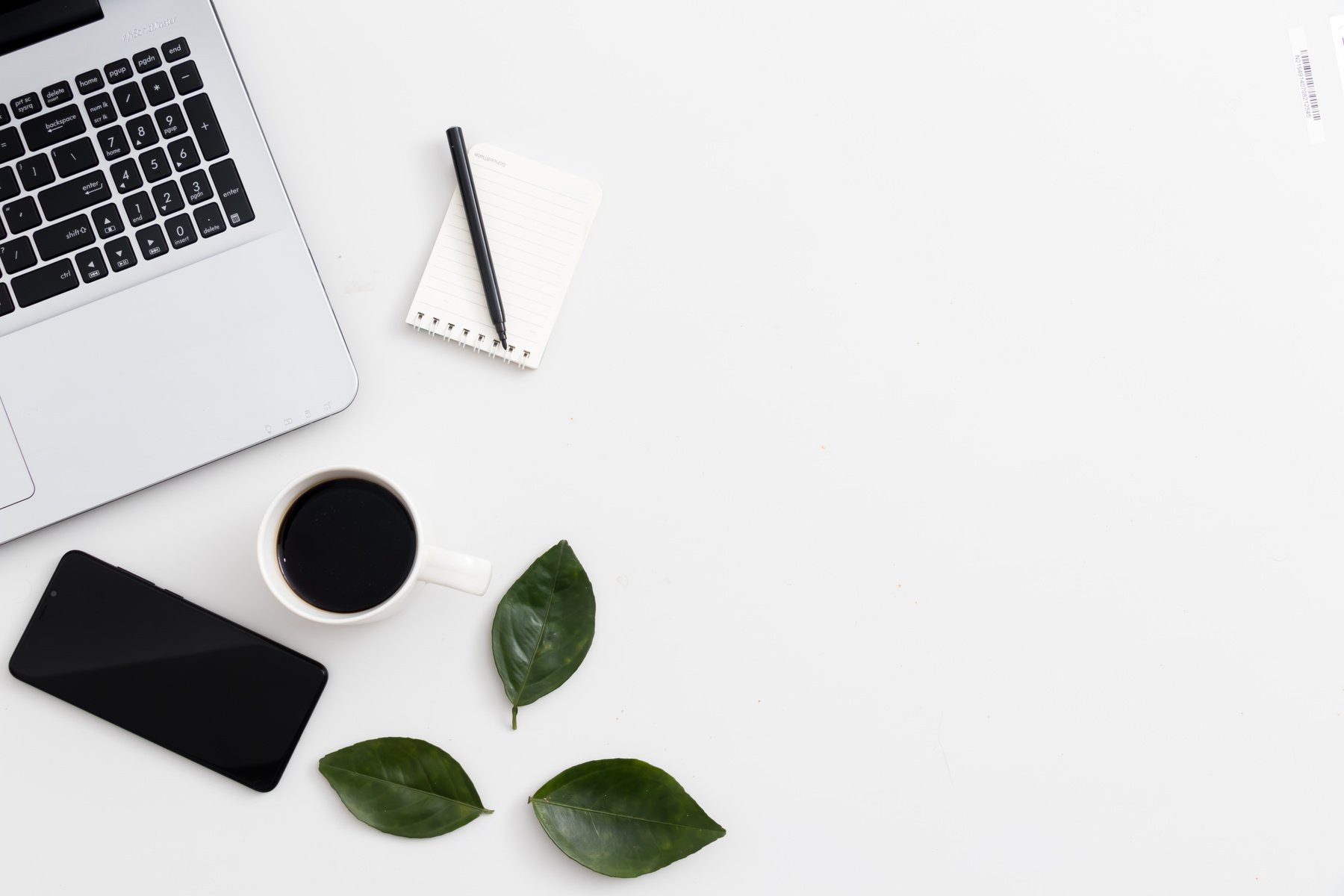 White office desk with laptop office plant and notebook and mobile phone